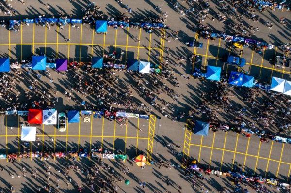 Tents, people and yellow parking spaces are seen from an above drone photo.  